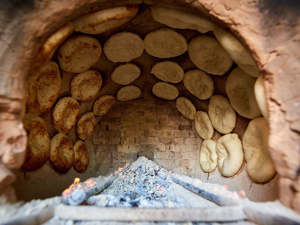We vragen de naam van Indische oven die kan bestaan uit een cilindervormige kuil in de grond of een gemetselde ton. De werking lijkt op die van een steenoven, met dit verschil dat de opening zich aan de bovenzijde bevindt.  Als de oven na voorverwarmen met houtskool op de bodem gloeiend heet is , wordt het gerecht erin geplaatst. Broden, zoals roti en naan, worden tegen de zijkanten gedrukt en vlees wordt op spiesen boven de gloeiende kolen geplaatst.  Wat is de Indische naam van deze oven? Moest je twijfelen de “ i “is niet nodig.