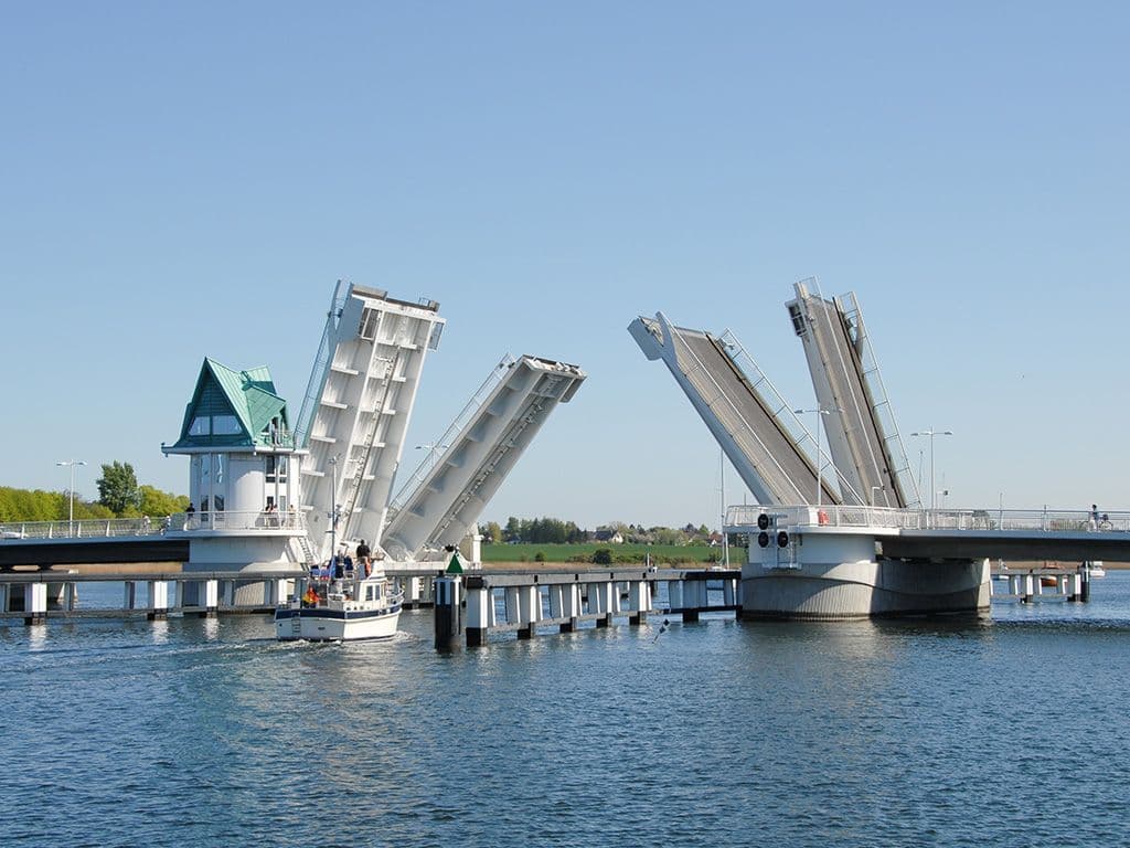 Op het scherm ziet u een beweegbare brug, waarvan het brugdek open en dicht klapt. Het speciale aan deze brug is dat het gewicht van het brugdek gecompenseerd wordt door een contragewicht, dat soms onder de grond in een kelder zit. Het openen en sluiten van de brug vraagt daardoor veel minder energie. De naam van dit brugtype is gebaseerd op een toestel dat u in veel huisartsenpraktijken terugvindt en waarvan de werking vroeger op dezelfde principes als dit type brug gebaseerd was. Hoe wordt dit brugtype genoemd?