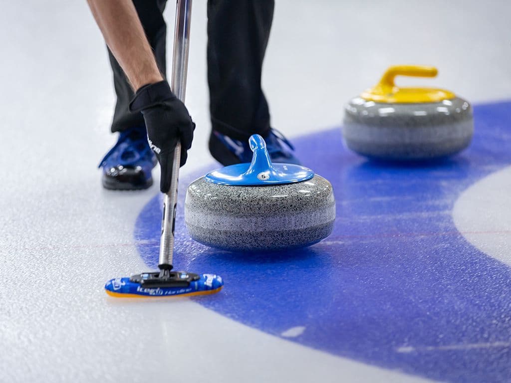 Bij welke wintersport probeert de skip de steen zo dicht mogelijk bij de dolly te schuiven, terwijl zijn teamgenoten de richting en snelheid van de steen met borstels proberen te beïnvloeden?