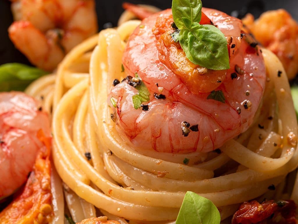 Welke Italiaanse pastasoort heeft een lange, smalle en platte vorm, lijkt sterk op spaghetti maar is licht afgeplat, is afkomstig uit Ligurië en wordt traditioneel geserveerd met vissauzen, schelpdieren of klassieke combinaties zoals pesto en zeevruchten?