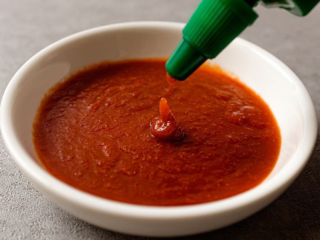 Ice ice baby, dat liedje kan wel door het hoofd spoken na het proeven van deze scherpe chilisaus! De saus is een vernoemd naar een kuststad in Thailand en wordt vervaardigd uit chilipeper, azijn, knoflook, suiker en keukenzout. Bekende merken zijn bijvoorbeeld Go-tan en Flying Goose. Hoe heet deze saus?