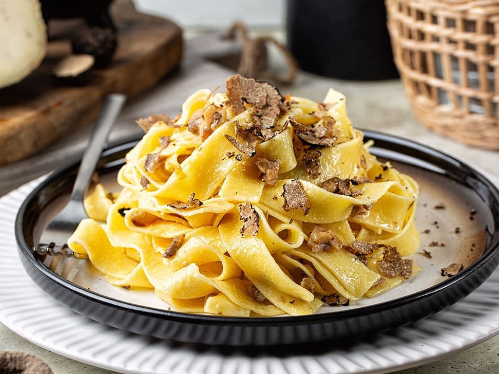 Welke klassieke Italiaanse pastasoort heeft lange, platte linten, is smaller dan pappardelle maar breder dan linguine, vindt zijn oorsprong in Emilia-Romagna en wordt traditioneel geserveerd met rijke vleessauzen, zoals de beroemde ragù alla bolognese?